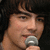 A person with dark hair holds a silver microphone, shown in four where the mouth and head position shift slightly