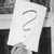 A grayscale icon featuring a large question mark on a white background with dark gray and black surrounding shapes.