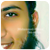Pixelated close-up of a person's face showing eye, eyebrow, nose, mouth, and ear with visible skin tones and dark hair against light background.