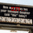 A static image of a sign with red text and blurred background elements, showing partial words like "m..." and "damp it.".