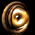 Golden circular object with concentric rings and a central dark dot, shown in multiple rotational states against black background.