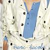 A person wearing a white jacket with black polka dots over a blue shirt, with visible hands and a partial view of the face.