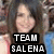 Pixelated image of a person with long dark hair and light skin, wearing pink clothing, overlaid with black text reading TEAM SALENA.