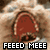 Pixelated image of a red, heart-shaped object with brown edges against a blurred background, featuring bold white text reading "FEEED MEEE" at the bottom.