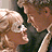 Two people in close physical proximity with one person's face near the other's cheek, rendered as a pixelated static image.