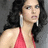 Pixelated image of a person with long dark hair wearing a red sleeveless top and large silver earrings against a gray background.