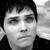 Black-and-white image of a person with short dark hair against a light background, paired with pixelated text fragments on dark
