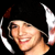 Pixelated static image of a person's face with dark hair and white ear-like shapes on the sides, set against black background.