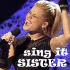 A person with a high ponytail holds a microphone, wearing a black shirt with text, against a blue background with white text.