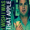 A person in a light blue shirt holds a green and yellow apple slice against a teal background with vertical text reading "I WISH I WAS THAT APPLE".