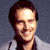 Static pixelated image of a person with dark hair and light skin wearing a white shirt against a gray background.