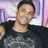 Pixelated image of a person with short dark hair wearing a black shirt, set against a blurred background with purple and pink tones.