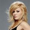 Static image of a woman with long blonde hair wearing a black strapless top and large earrings against a gray background.