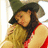 Two people embrace; one wears a red sleeveless top and dark hat, the other has long light hair. Bright green background with pink text.