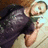 A person in a dark shirt lies on a light surface holding a small object, with a headband visible on their head.