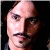 Pixelated close-up of a person's face with light skin tone, dark eyes, and dark mustache against dark background.