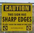 Static yellow warning sign with bold black text and two circular symbols on a blurred background.
