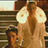 Two figures with long brown hair stand side-by-side, each holding a circular white object with a small central dot.