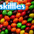 Pixelated image of colorful Skittles candies with three distinct 'skittles' text overlays in blue, pink, and yellow.