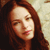 A static pixelated image of a person with long brown hair, light skin, and a neutral expression against a light background.