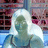 Pixelated static image of a figure with light-colored hair and greenish skin wearing blue clothing against a background with pink, purple, and blue tones.