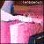 Pixelated image of two figures in close embrace, one with light blue hair and white clothing, the other with brown hair and pink tones, against a dark background.