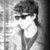 Black-and-white animated icon of a person with dark hair and sunglasses, shown in two poses with a gray background.