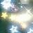 A static pixelated image featuring multiple star shapes in yellow and white against a blurred background of blue, green, and purple hues.