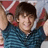 A pixelated image shows a person with dark hair wearing a blue striped shirt, holding a red and white object near their head.