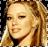 Pixelated close-up of a person with light brown hair, closed eyes, and a neutral expression against a dark background.