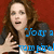 A woman with long brown hair in a black jacket over white top against red background, hands raised near chest.