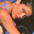 Pixelated close-up of a person's upper body and face with visible skin tones, dark hair, and partial clothing details against a blue background.