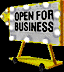 A pixelated sign with 'OPEN FOR BUSINESS' text on a lighted marquee, mounted on a yellow wheeled base against a black background.