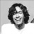 Black-and-white pixelated static icon of a person with dark curly hair and a light-colored shirt against a plain background.