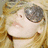 A blonde woman wearing dark sunglasses with a reflective lens, her head tilted slightly upward and to the right, captured in a pixelated close-up.