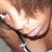 Pixelated close-up of a person's lower face and neck with visible skin tones, dark hair strands, and a black strap across the chest.