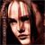Pixelated close-up of a person with light brown hair styled in two long braids framing the face, set against a dark background.