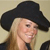 Pixelated image of a person with long blonde hair wearing a black cowboy hat and dark clothing against a light background.