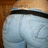 A pixelated close-up of light blue denim fabric with a black waistband, set against a brown textured background.