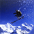 Pixelated static image of a skier in mid-air against blue sky and white clouds, with visible dithering and low-resolution rendering artifacts.