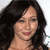 A pixelated close-up of a person with long dark hair, light skin, and a slight smile, set against a light background.