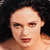 Pixelated close-up of a person with light skin tone, dark hair, and red lips against a dark background.