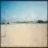 Pixelated beach scene with light blue sky, sandy shore, and distant horizon line next to text reading 'Beach Volley-Ball' in dark gray block letters.