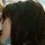 A static image shows a person with dark hair and a light-colored sleeve, partially visible against a dark background with subtle color variations.