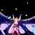 Pixelated figure in pink dress with dark hair, arms raised against dark background with scattered light patches.
