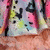 A colorful pixelated icon with a pink and brown background, featuring repeated black triangular shapes on a light blue base.