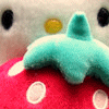 A plush toy with large black eyes and a yellow nose rests on a red mushroom with white spots, with a light blue star-shaped object in the foreground.