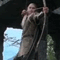 A figure in a brown tunic and dark pants climbs a rope against a backdrop of blue sky and green foliage, captured in a sequence of showing motion progression