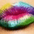 Four identical pixelated lips with rainbow gradient colors on a light brown background.