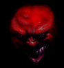 Red-skinned demonic face with sharp teeth, wide eyes, and a distorted expression against black background.